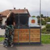 Composteur de chez Abriplus en acier et bois, avec signalétique et une personne devant