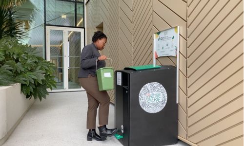 Abribac la consigne verte installé à l'extérieur et une personne verse ses biodéchets dedans